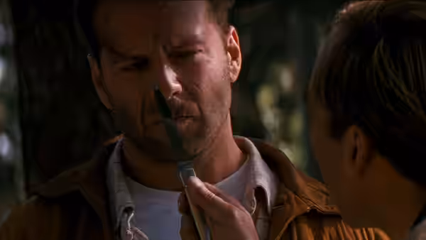 Joe Hallenbeck (Bruce Willis) studies a knife held near his face as a girl watches