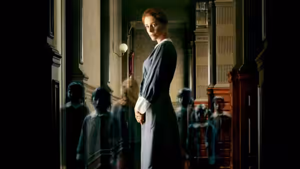 Laura (Belén Rueda) stands in a hallway among ghostly children