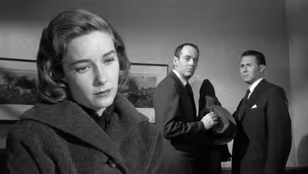 Rose Balestrero (Vera Miles) fills the foreground as two suited men stand behind her