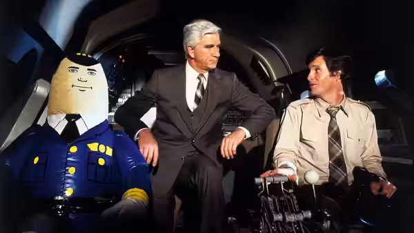 Pilot dummy sits with two suited men inside airplane cockpit