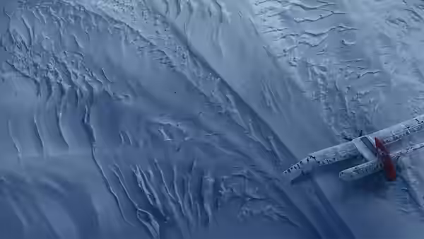 A crashed plane lies partly buried in a rippled expanse of snow