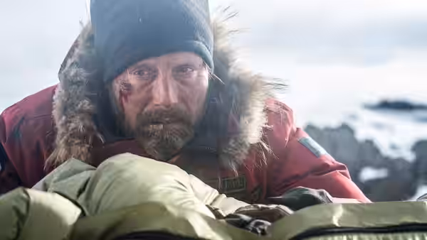 H. Overgård (Mads Mikkelsen) tends to an injured woman wrapped in a sleeping bag