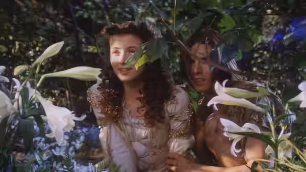 Princess Lili and Jack hide among flowering plants in the forest