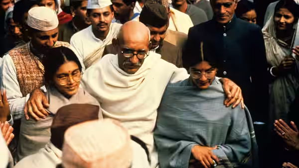 Gandhi (Ben Kingsley) embraces two young women during a public gathering