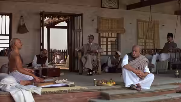 Gandhi (Ben Kingsley) sits among several men inside a large room