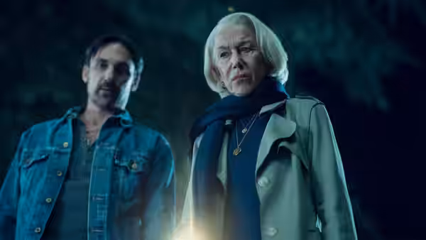 Elizabeth and a man standing outdoors at night with flashlight nearby
