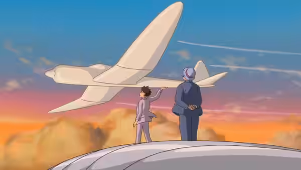 A young man in a suit points at a large white airplane beside an older man