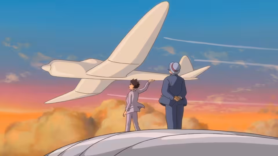 A young man in a suit points at a large white airplane beside an older man