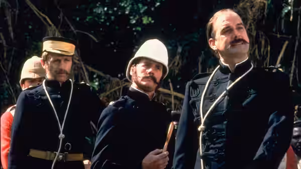 Three officers in military uniforms stand among trees in a jungle setting