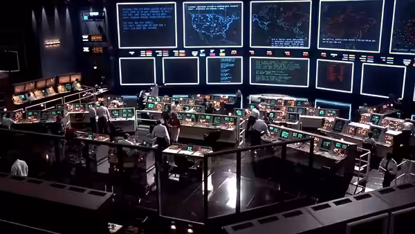 Technicians working at computer consoles in a dimly lit command center