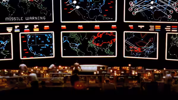 Personnel in a missile warning control room with large display screens