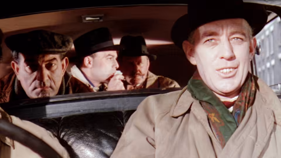 Harry (Peter Sellers) and the gang ride in a car, with Harry leaning out the window
