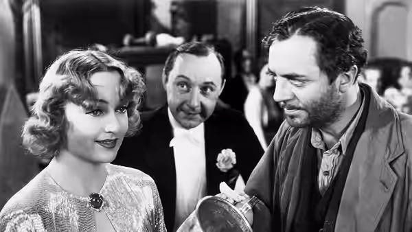 A woman watches a bearded man examine a compact as another man looks on