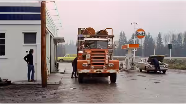 An orange truck is parked at a rural gas station