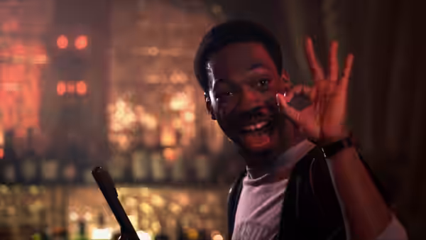 Axel Foley (Eddie Murphy) smiling and making an OK gesture in a bar