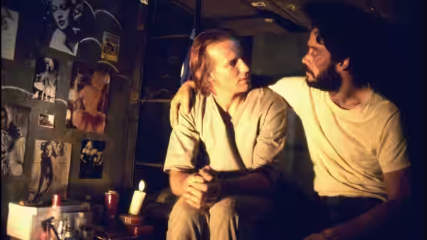 Luis Molina (William Hurt) sits with arm around Valentin Arregui (Raul Julia)