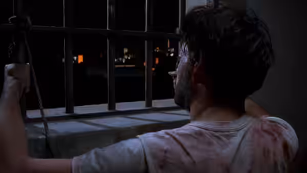 Valentin Arregui (Raul Julia) grips prison bars while looking out at night
