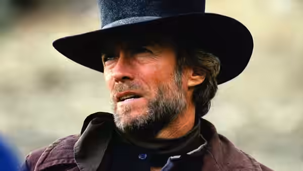 Preacher (Clint Eastwood) wearing a black hat and dark coat outdoors