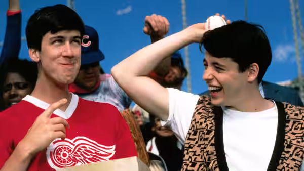 two young men at a baseball stadium one laughing while holding a ball