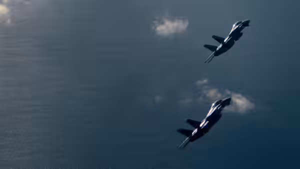 Two fighter jets fly in formation over the open ocean