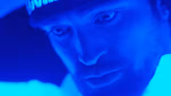 Man in a cap looks aside under blue light in close-up