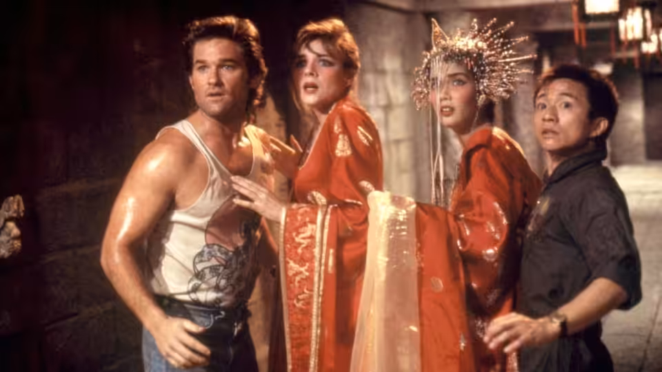 Jack Burton (Kurt Russell) stands with Gracie Law (Kim Cattrall) and two others in red robes