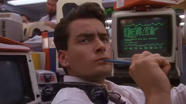 Bud Fox (Charlie Sheen) chews a pencil while studying a computer screen