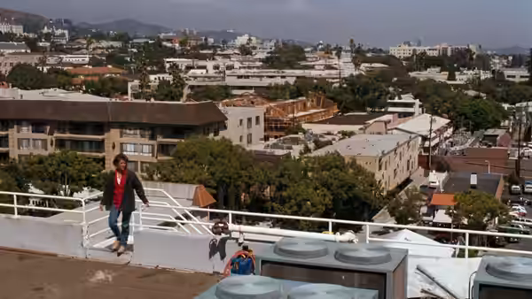 Martin Riggs (Mel Gibson) skateboarding on a rooftop overlooking the city