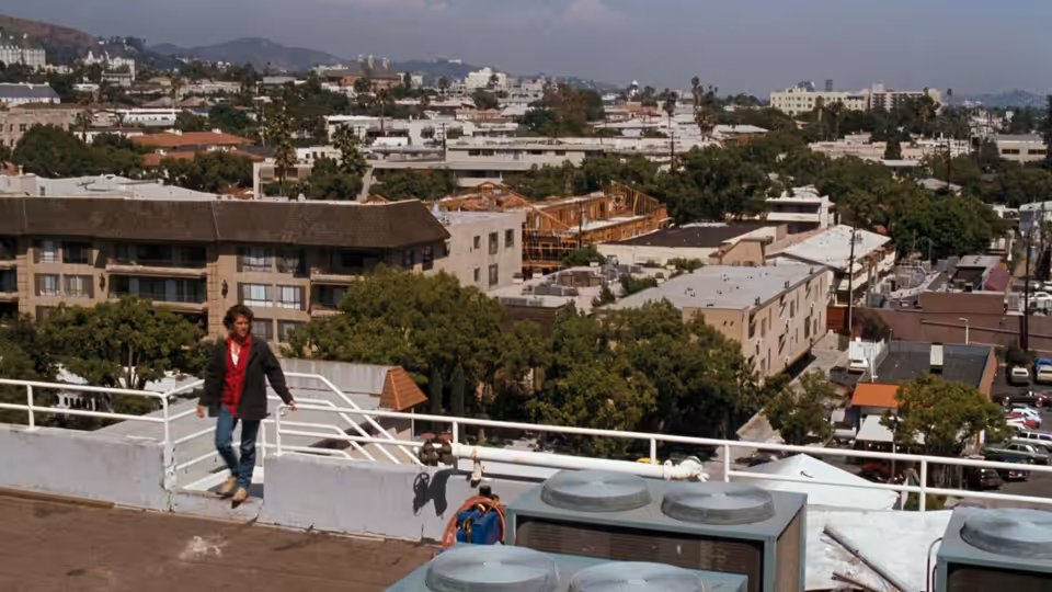 Martin Riggs (Mel Gibson) skateboarding on a rooftop overlooking the city