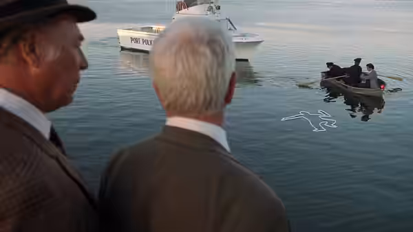 Frank Drebin (Leslie Nielsen) and another man watch a police boat and floating outline