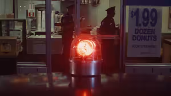 A red police light flashes inside a donut shop at night