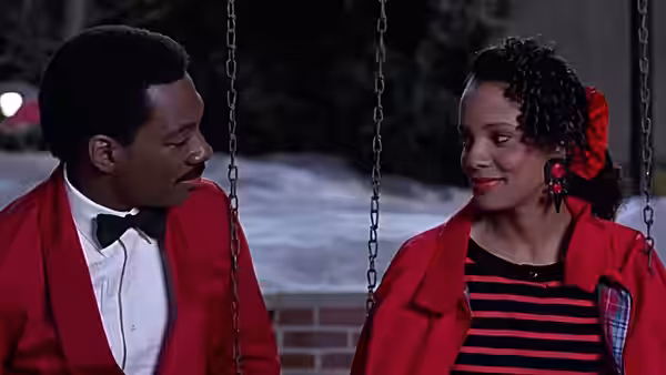 Prince Akeem (Eddie Murphy) and Lisa (Shari Headley) sitting on swings in formal wear