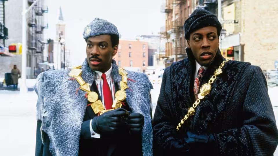 Eddie Murphy and Arsenio Hall in ornate robes with gold chains on a snowy street