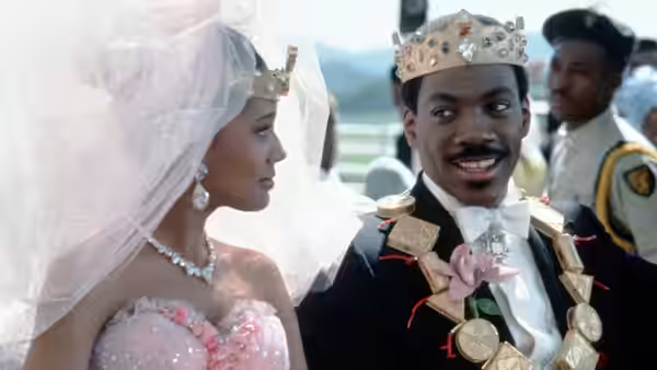 Prince Akeem (Eddie Murphy) and Lisa (Shari Headley) wearing crowns at an outdoor event
