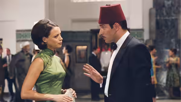 Larmina (Bérénice Bejo) speaks with Hubert Bonisseur de La Bath (Jean Dujardin), wearing a red fez