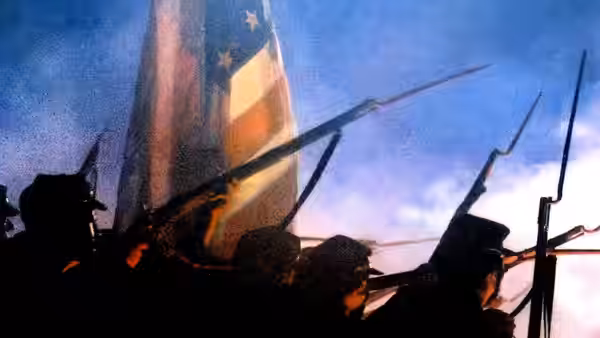 Silhouetted infantry advancing with bayonets under a large American flag