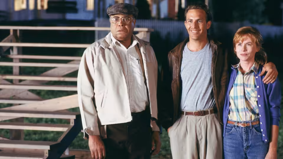 Terrence Mann (James Earl Jones), Ray Kinsella (Kevin Costner) and Annie Kinsella (Amy Madigan) stand on wooden bleachers