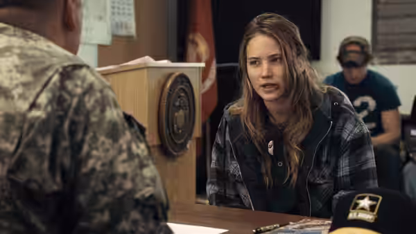Ree Dolly speaking to a military officer at a desk