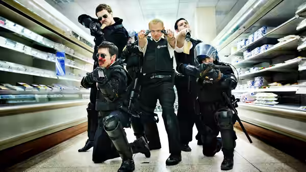 Nicholas Angel (Simon Pegg) and armed officers aiming guns in a supermarket
