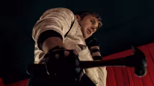 Driver (Ryan Gosling) in a white jacket grips a hammer and looks upward in darkness