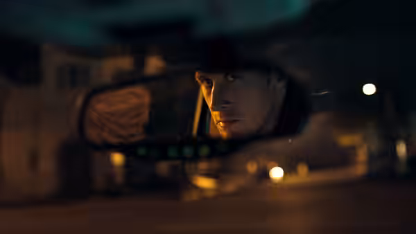 Driver (Ryan Gosling) glances into the rearview mirror while driving at night