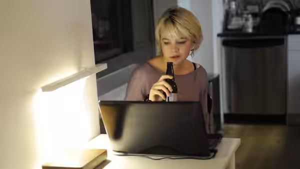 Sissy (Carey Mulligan) drinking beer while using a laptop at night