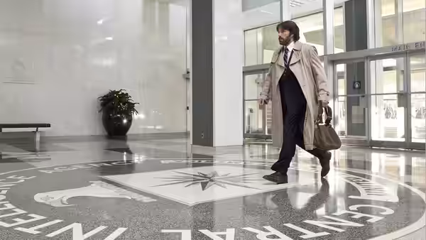 Tony Mendez walks across a polished lobby floor carrying a bag