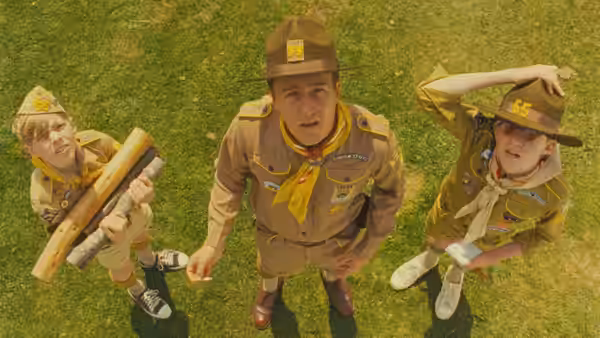 Scout Master Ward (Edward Norton) with two scouts on a grassy field