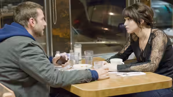 Pat (Bradley Cooper) and Tiffany (Jennifer Lawrence) talking across a restaurant table