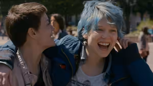 Emma (Léa Seydoux) laughing outdoors with a short-haired friend beside her