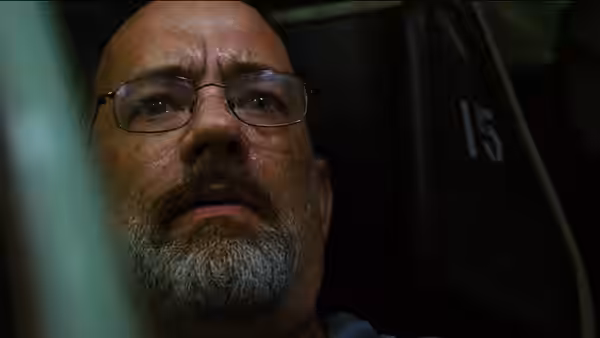 A bearded man with glasses sits inside a dark enclosed space