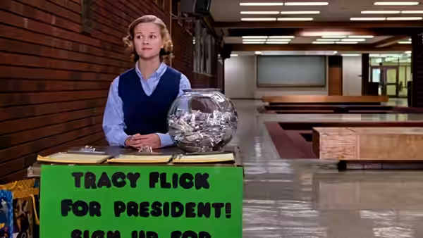 Tracy Flick (Reese Witherspoon) stands behind her campaign table in an empty hallway