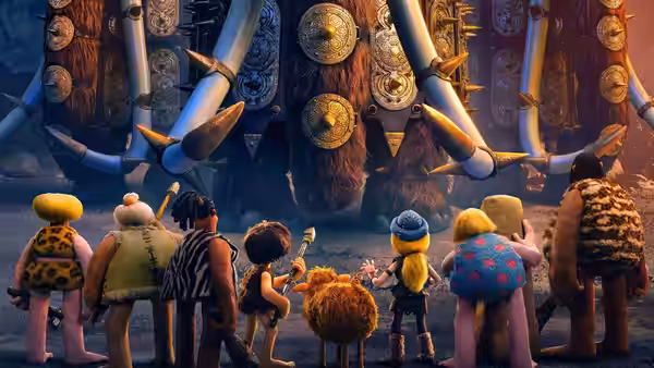 A group of Stone Age villagers face enormous decorated gates lined with weapons