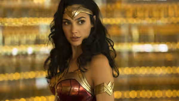 Diana Prince (Gal Gadot) turns toward someone in a gold-lit interior